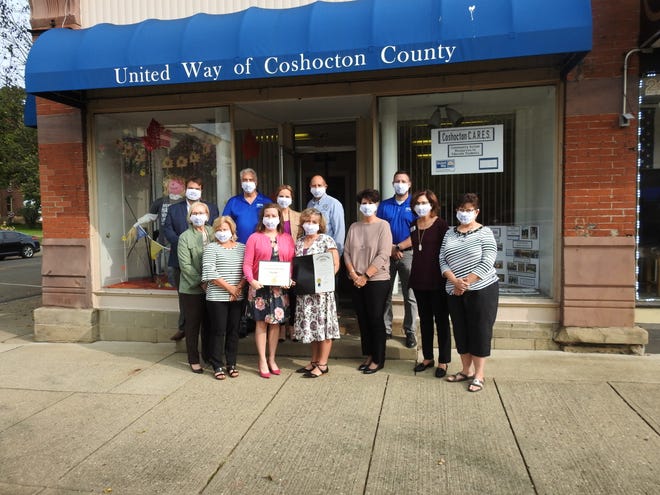 Employees, board members and local dignitaries with proclamations presented by State Sen. Jay Hottinger and Tim Ross from the office of Congressman Bob Gibbs honoring the local organization's 80 years in the local community in front of the United Way of Coshocton County office on Main Street.