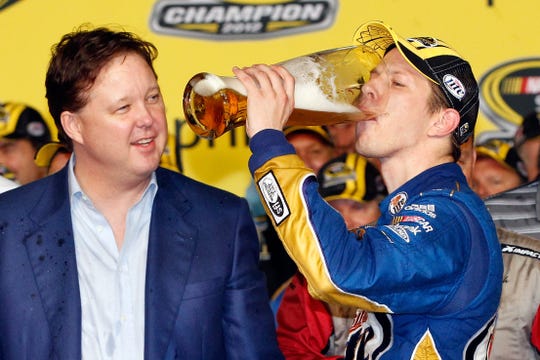 Brad Keselowski chugs a huge beer in front of NASCAR chairman and CEO Brian France at Homestead-Miami Speedway after winning the 2012 NASCAR Sprint Cup championship.