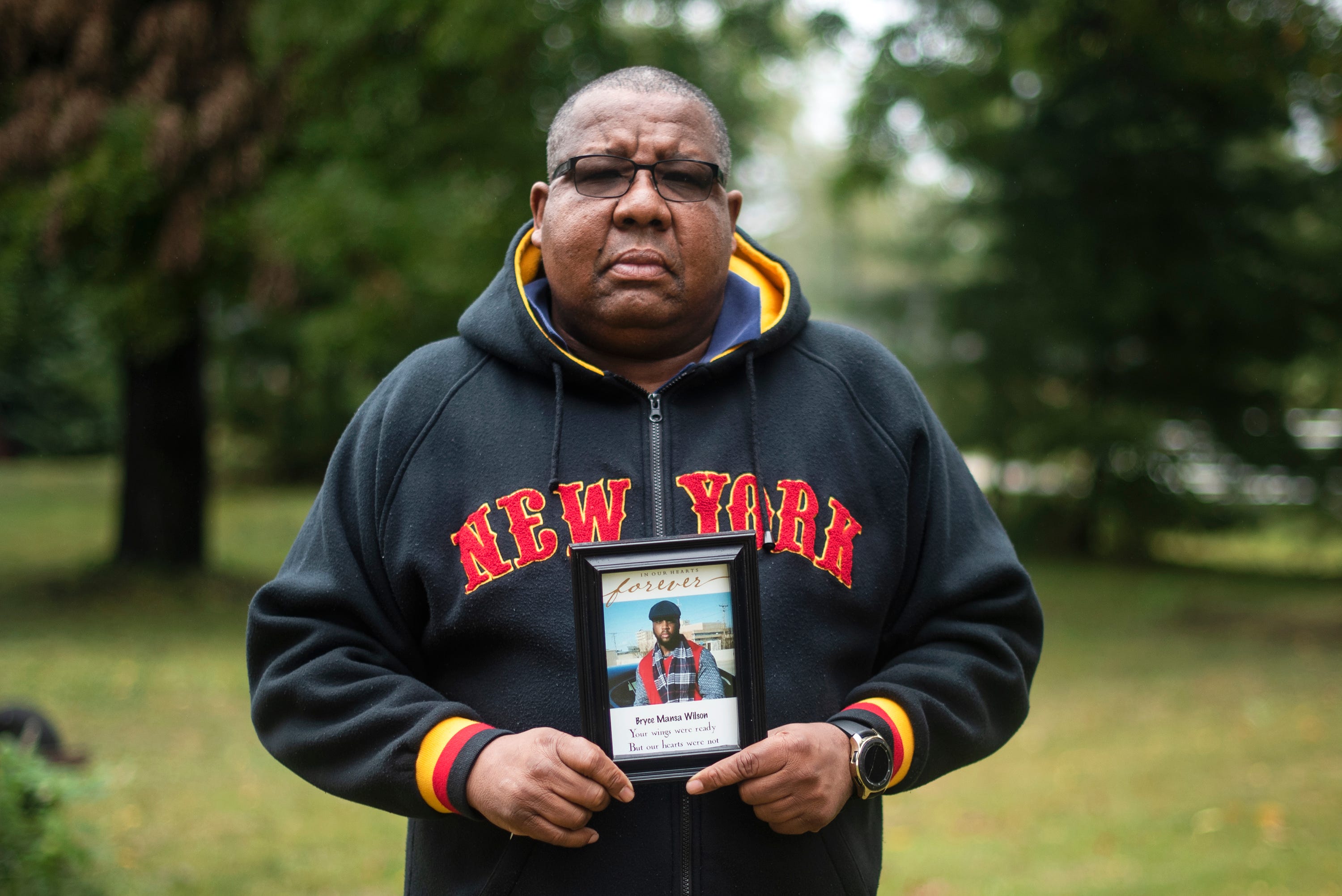 Broderick Daye poses for a photo with a portrait of his nephew Bryce Wilson, who died of COVID-19.