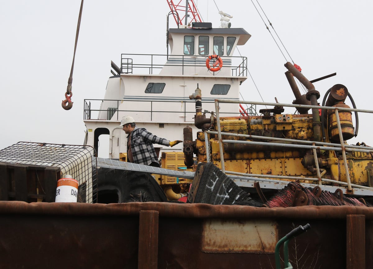 Mike Vinik navigates heavy equipment moored on barges alongside his tugboats at "Vinik Island," his agglomeration of marine equipment in The Kills.