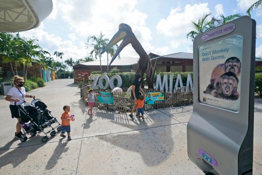 Visitors pass a hand sanitizer dispensing station as they visit Zoo Miami, Tuesday, Sept. 15, 2020, in Miami. The zoo reopened Tuesday as Miami-Dade and Broward counties moved to Phase 2 of reopening on Monday.
