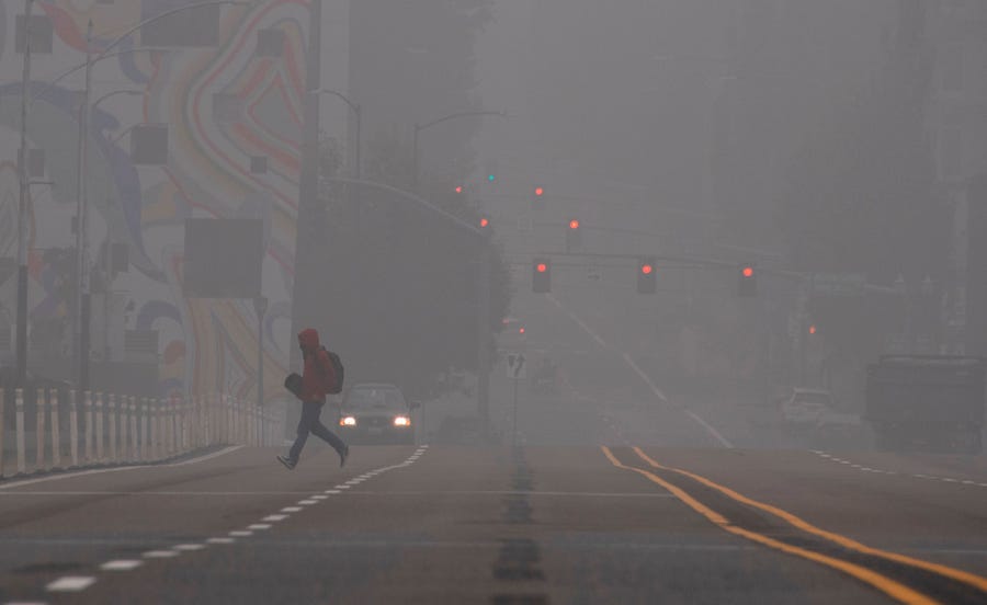 A man crosses a street in downtown Portland, Oregon as wildfires continue to burn in many parts of the state, September 14, 2020.  Smoke from wildfires and fog are blanketing the city.