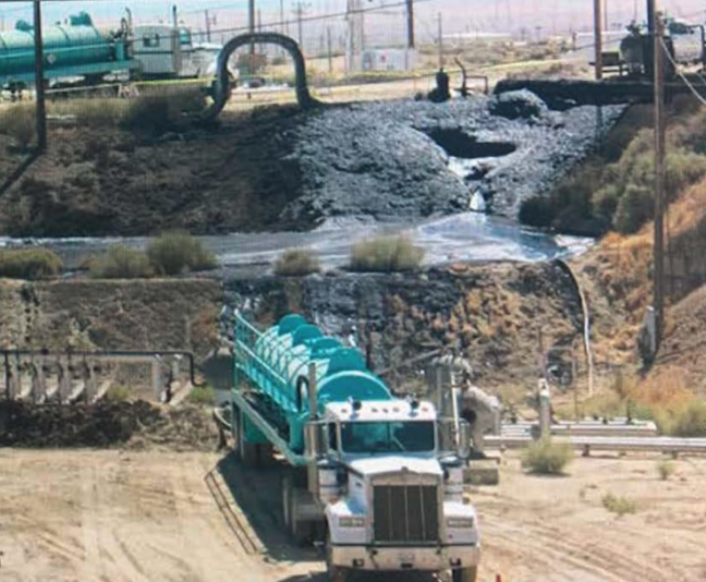 A truck vacuums up oil from a surface expression in the Cymric field.