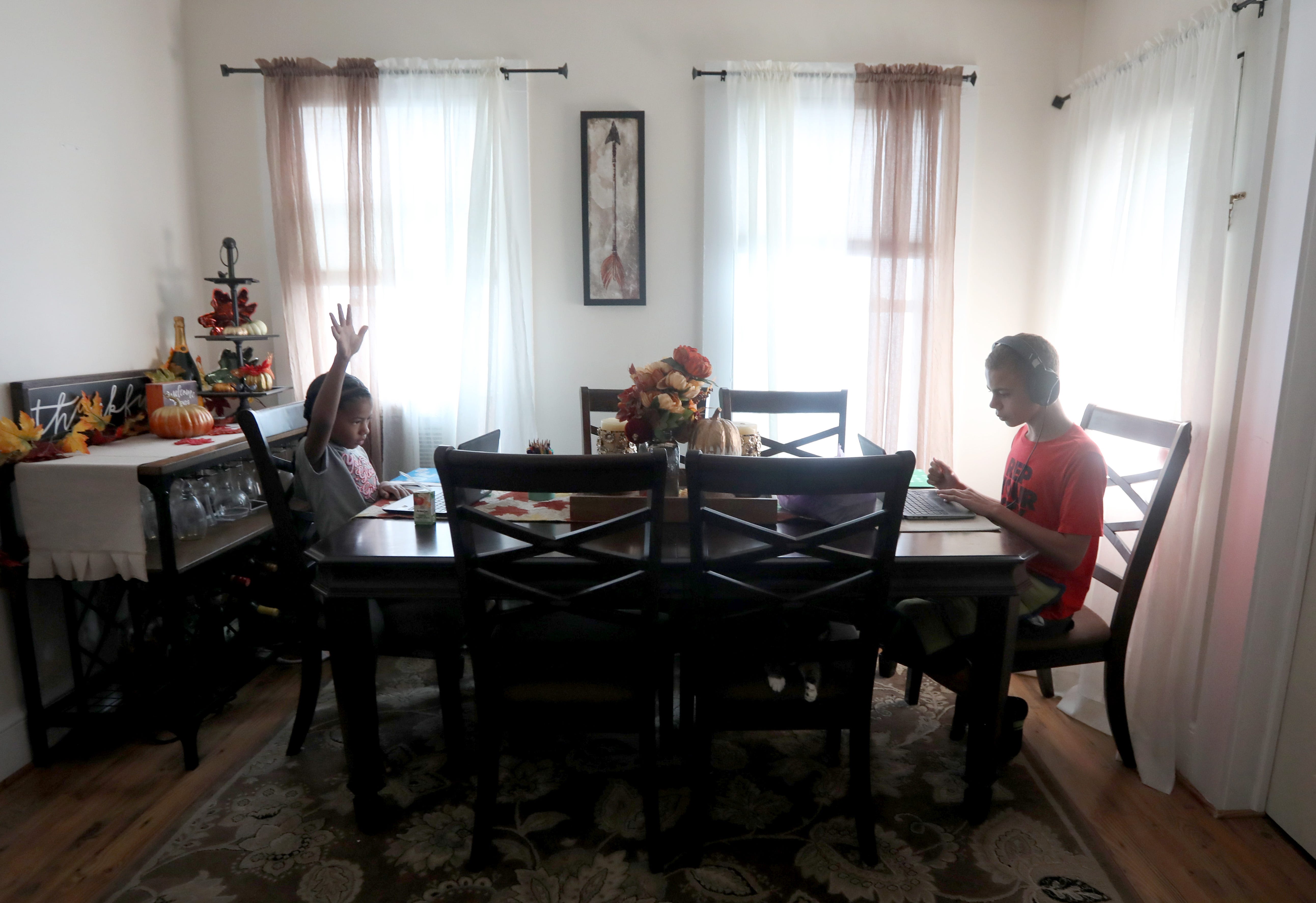 London Jansen, 7 raises her hand to be called on during an online class as she and brother Jordan, 12, attend virtual school while sitting at the dining room table of their Middletown, N.Y. home Sept. 16, 2020. All students in the Middletown school district are starting the school year with virtual classes due to the COVID-19 pandemic. 