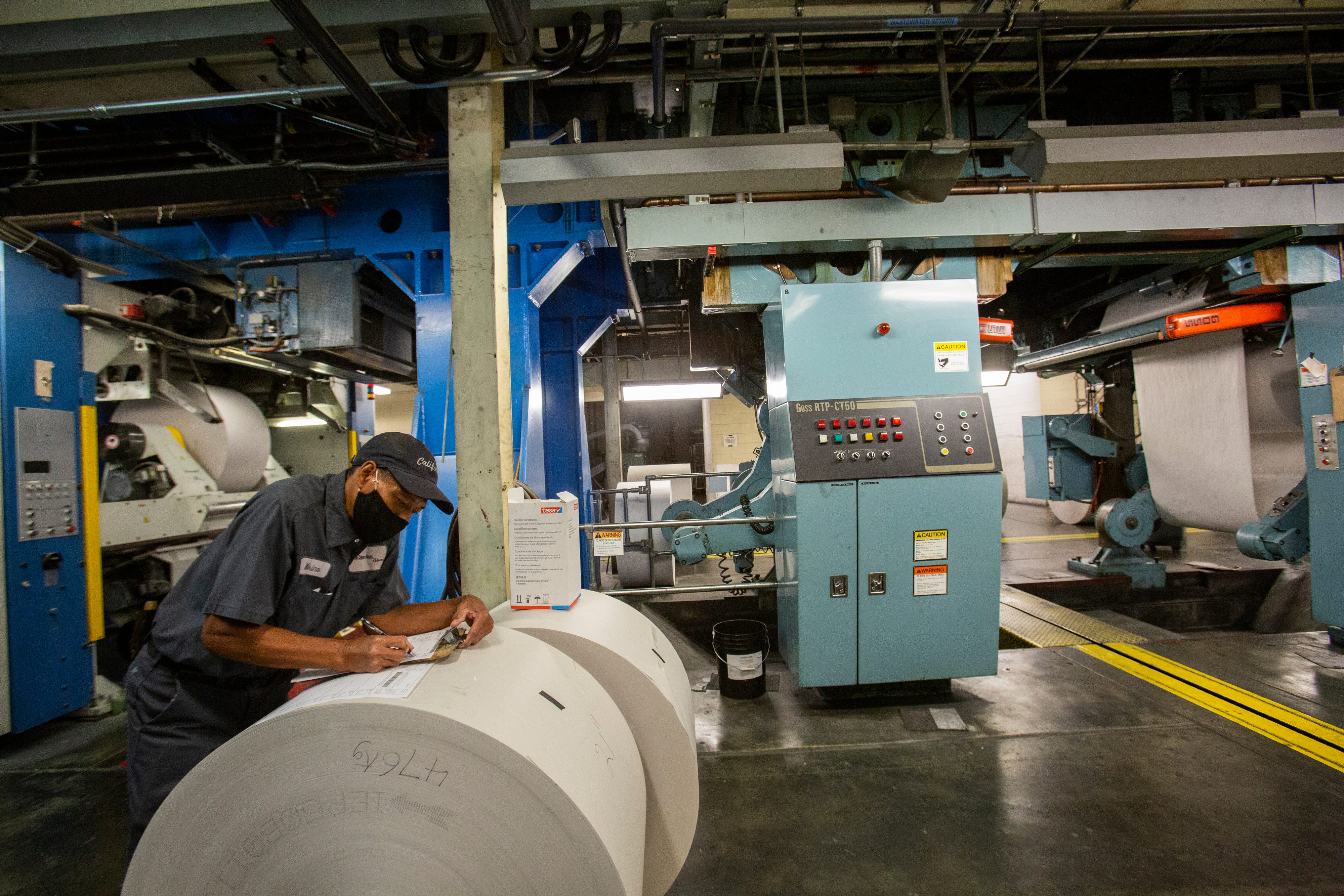 Marino Callorina, press operator, leans on a newspaper roll of paper to take notes of the day's work at the presses of The Desert Sun.