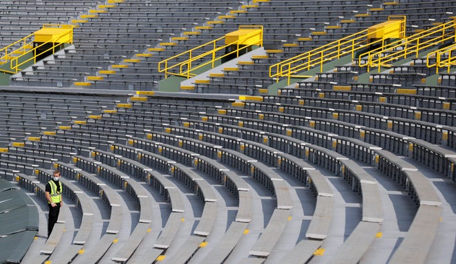 A security guard looks back toward the field while standing amidst the empty rows at Lambeau Field during the Green Bay Packers home opener against the Detroit Lions on Sept. 20, 2020, in Green Bay, Wis. Fans were not allowed to attend the game due to the coronavirus pandemic.