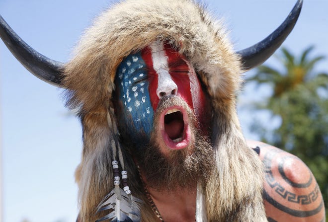 Jake Angeli, who supports QAnon, chants during a rally to open the state at Wesley Bolin Plaza in Phoenix on May 3, 2020.