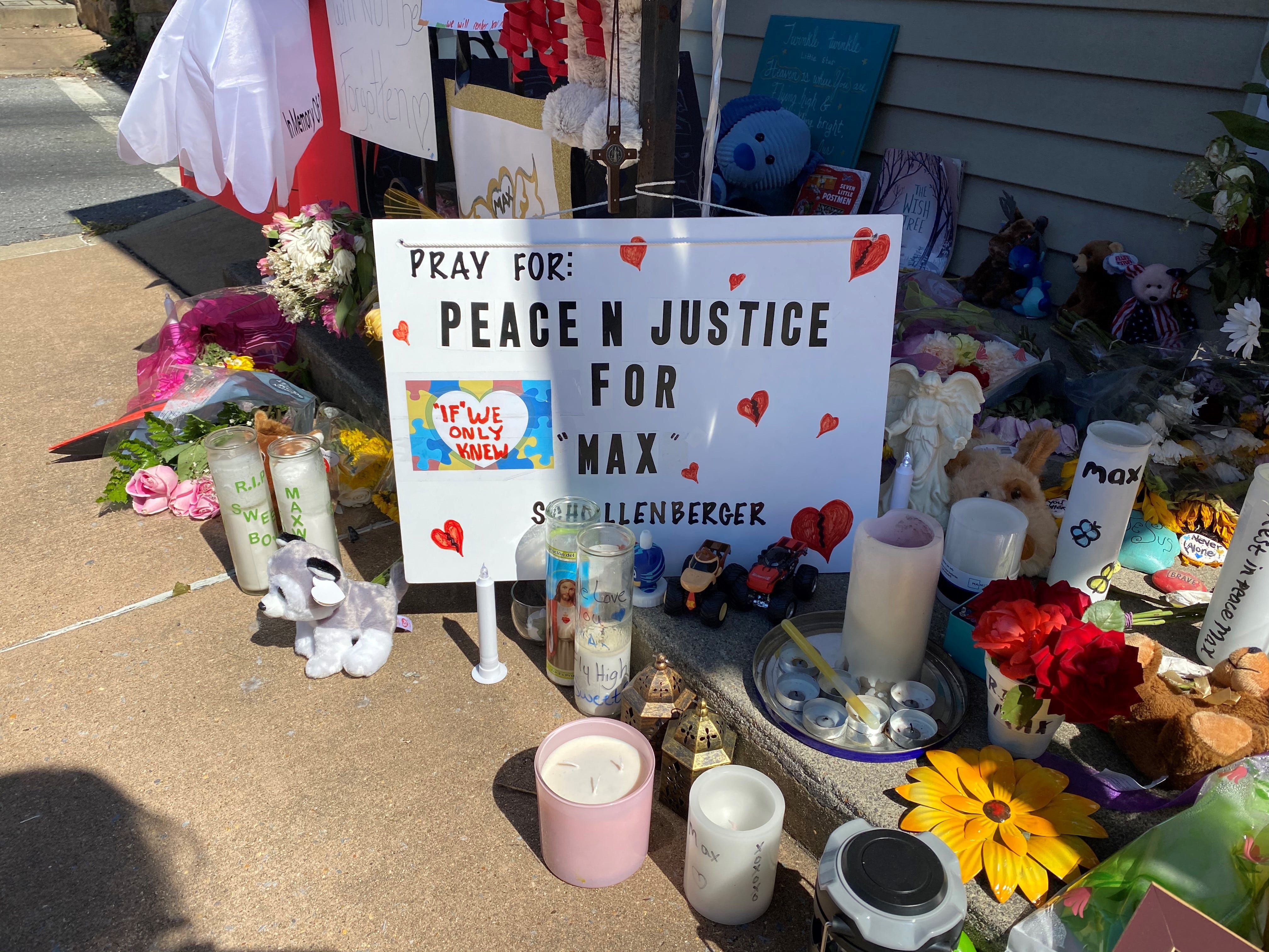 In 2020 candles, flowers, signs, balloons and teddy bears fill the front porch of Maxwell Schollenberger's home, including this one: Peace N Justice for Max.