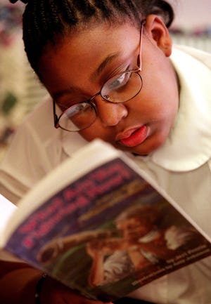 Student Kadesia Gantt reads a book about black inventor and scientist Benjamin Banneker.