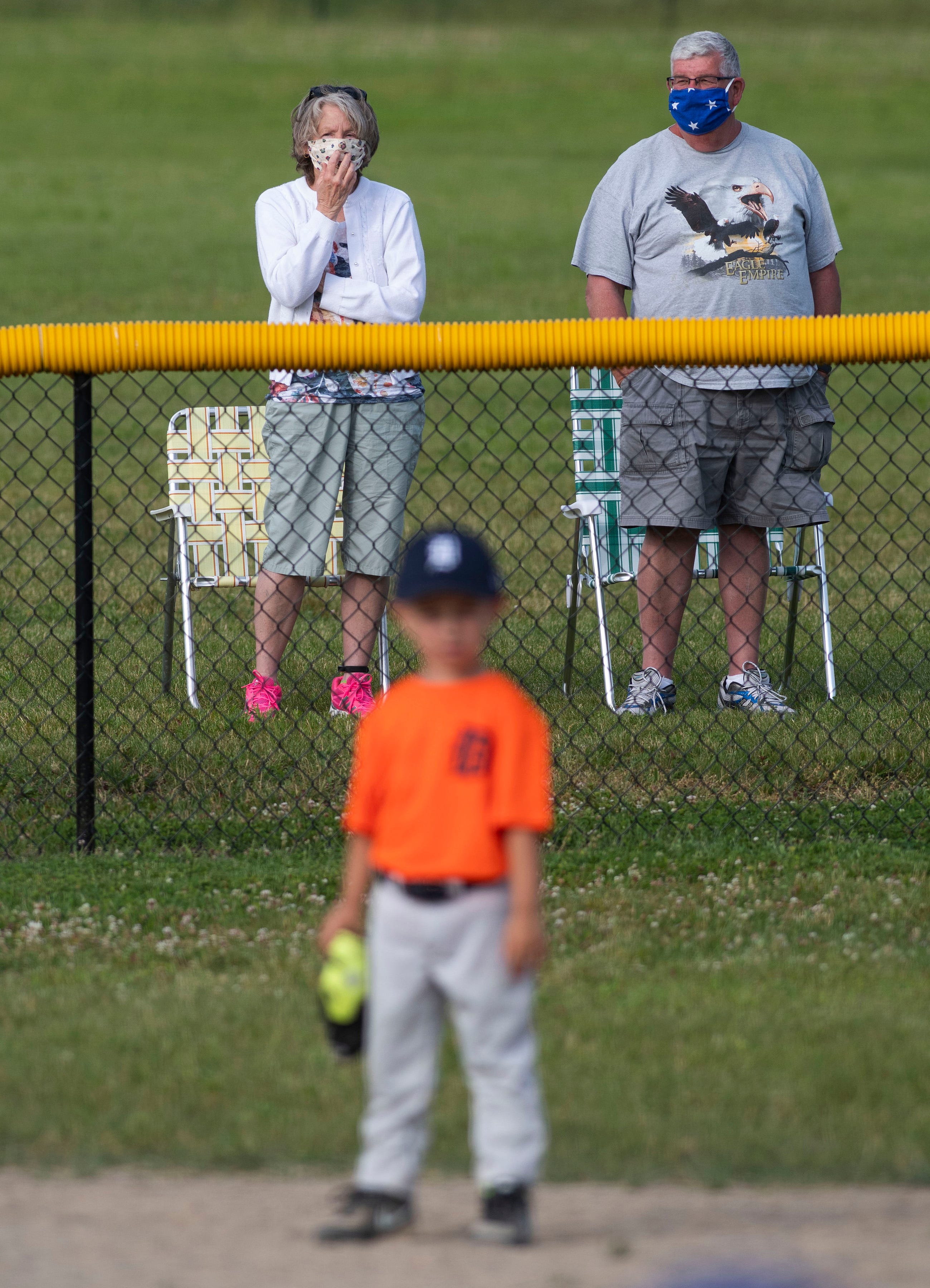 Masked spectators keep a safe distance as they watch a youth baseball game in Indianapolis on June 18.