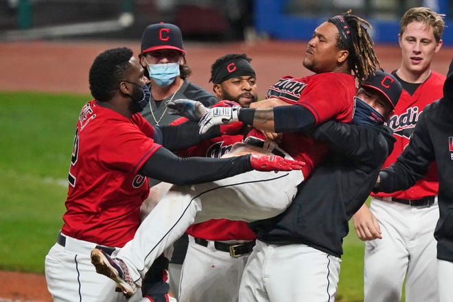 Cleveland Indians starting pitcher Carlos Carrasco, right, picks up Jose Ramirez as he celebrates with Franmil Reyes, left, after Ramirez hit a three-run home run in the tenth inning of a baseball game against the Chicago White Sox, Tuesday, Sept. 22, 2020, in Cleveland. The Indians won in ten innings. (AP Photo/Tony Dejak)