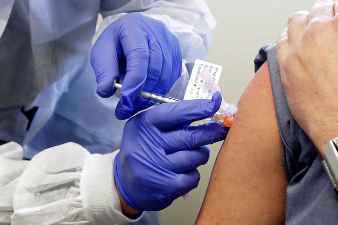 In this March 16, 2020, file photo, Neal Browning receives a shot in the first-stage safety study clinical trial of a potential vaccine for COVID-19.