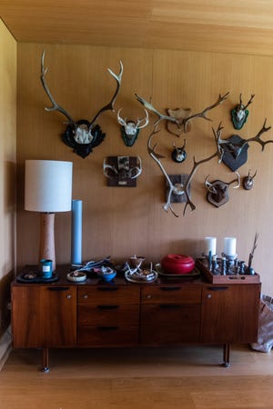Antlers adorn the wall above a midcentury console table.