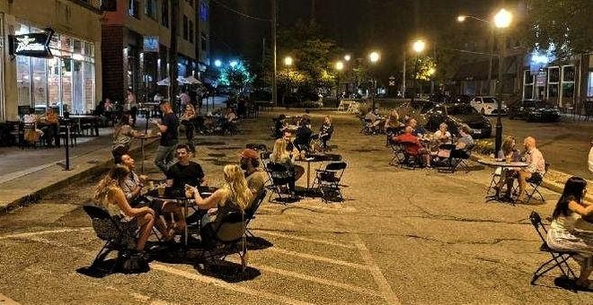 People dine and drink on a parking lot area converted into outdoor dining on Seventh Street near Braxton Brewing's taproom, McK's Chicks, and Rich's Proper Food and Drink restaurants.