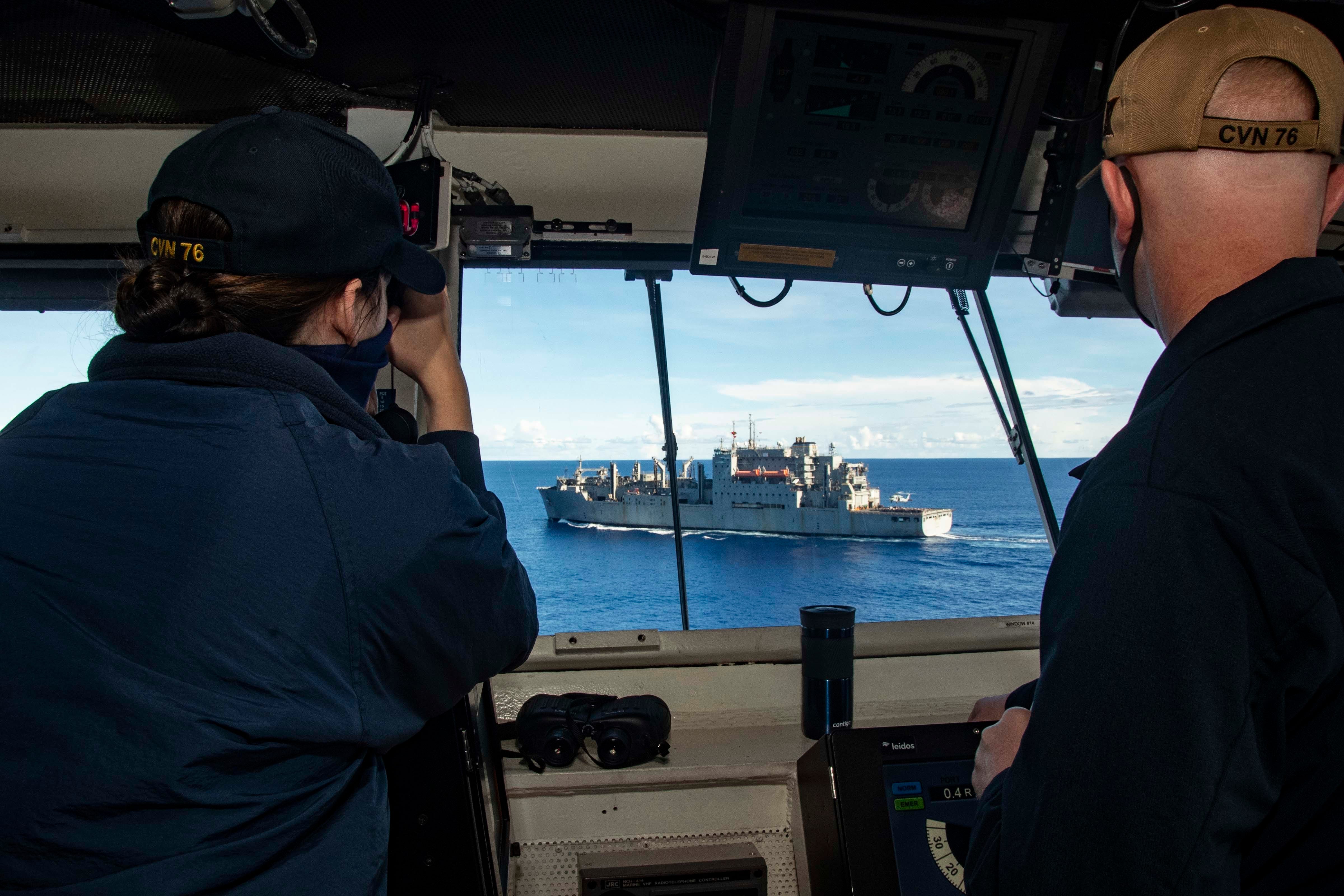 Lt. j.g. Mary Kate Corcoran, left, from Mercersburg, Pennsylvania, and Lt. j.g. Samuel Mobley, from Bloomington, Indiana, observe a replenishment-at-sea with dry cargo and ammunition ship USNS Alan Shepard from the pilothouse of the USS Ronald Reagan in support of Valiant Shield 2020 on Sept. 22, 2020.