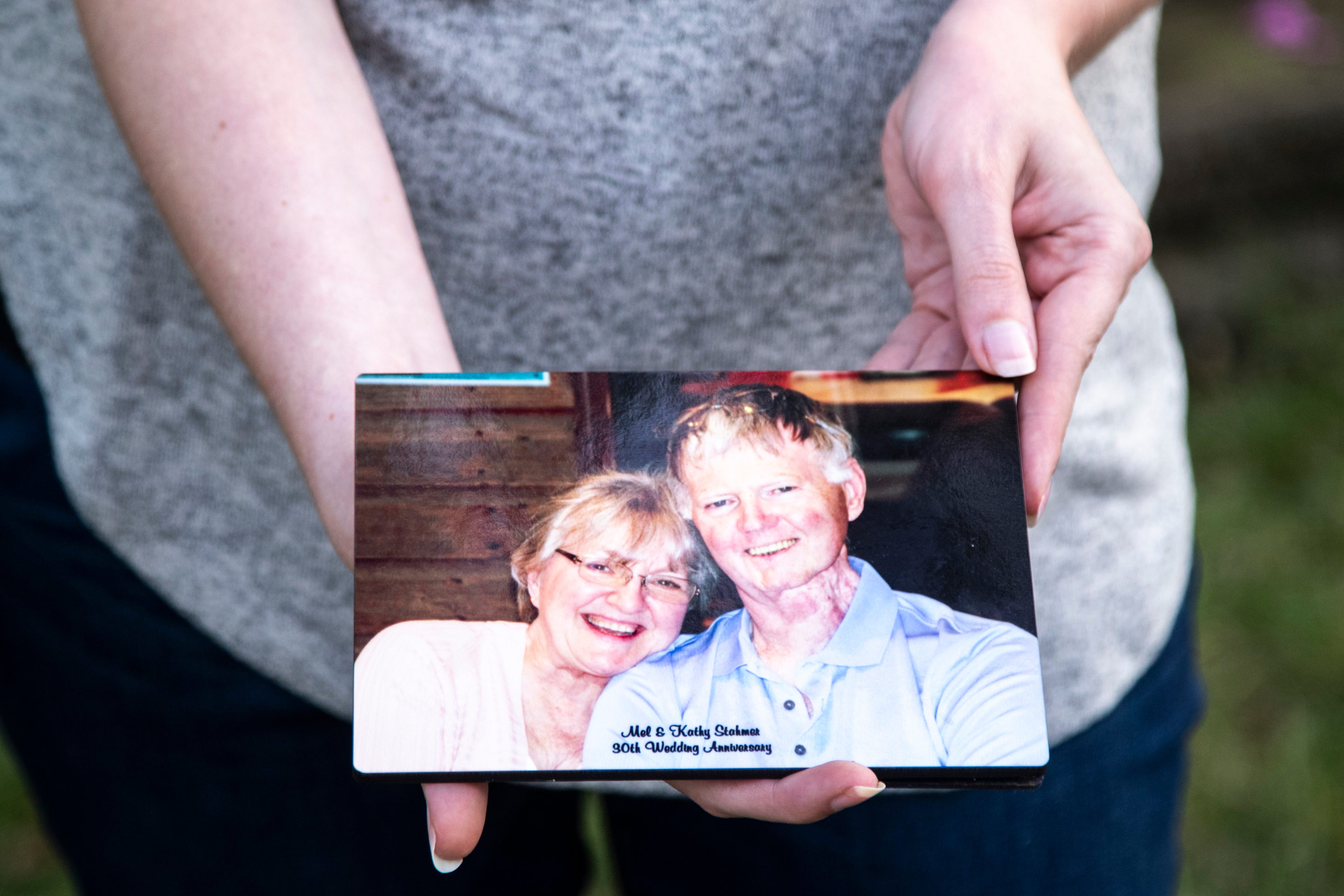 Kathy Stahmer poses for a portrait holding a picture of her husband, Mel, who died from COVID-19.