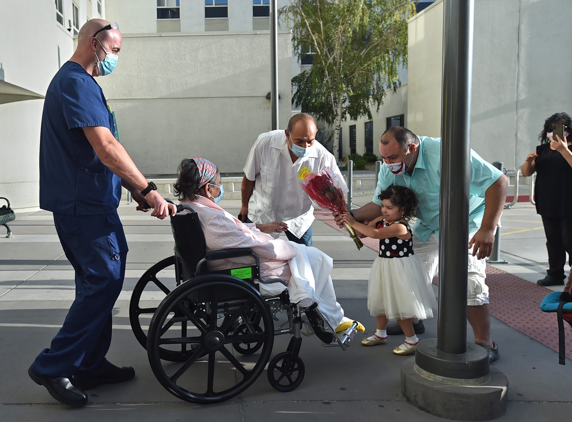 Patricia Villaseca's family approach her as she is wheeled out of from Saint Mary's Regional Medical Center after being hospitalized 5 months after contracting COVID-19 in April 2020. Left to right is her husband Jorge Franco, her son-in-law Chris Camacho and granddaughter Gadi, 4. They waited 2 hours for her to be discharged form the hospital.