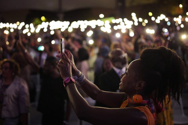 Crystal Fox of Atlanta takes photos of cell phones lit during an Aretha Franklin tribute concert at Chene Park Amphitheatre (now the Aretha Franklin Amphitheatre) in Detroit on Thursday, August 30, 2018.