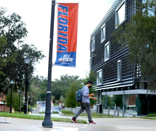 A student walks past a sign at the University of Florida as the first day of classes begin on Aug. 31. Gov. Ron DeSantis thinks some university policies go too far in disciplining students for socializing amid the pandemic.