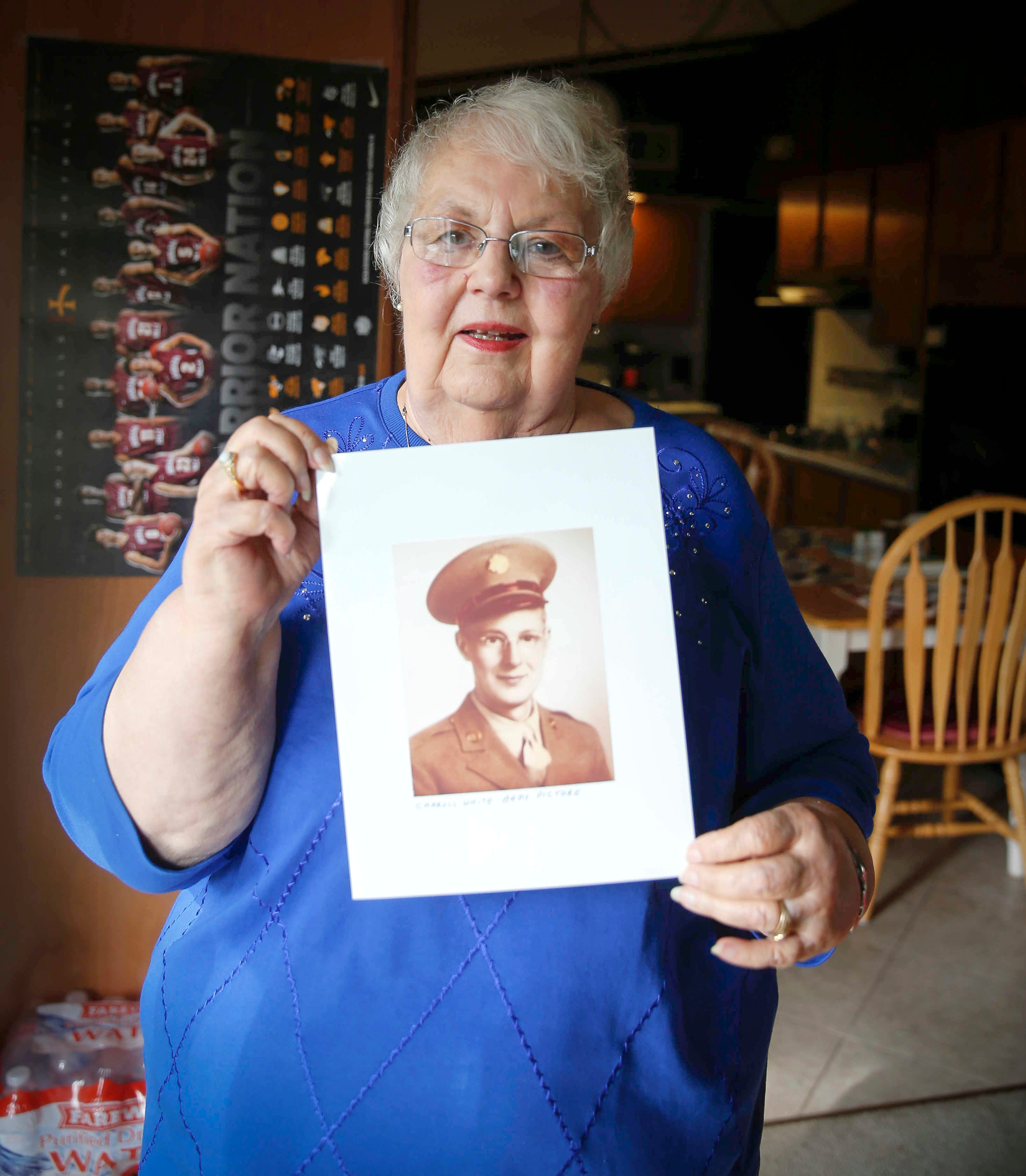 Lynne Blackwell poses for a photo with a portrait of her father, Carroll White, who died from COVID-19 shortly after his 100th birthday.