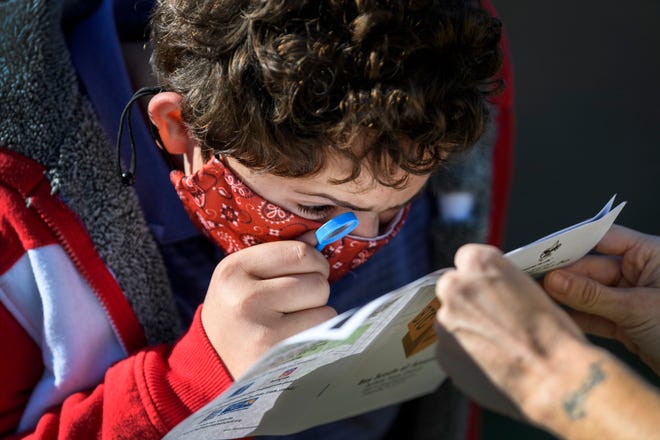Central High School student Miquel Gámez uses a small magnifying glass to look at pictures in a workbook with BSA Program Leader Samantha Taylor during the Exceptional Needs Scouting Program’s Virtual Fall Fun Day event held outside of CHS in Evansville, Ind., Tuesday morning, Sept. 29, 2020. 