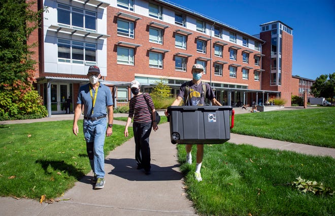 Freshman Jacob Roth, right, walks back with his parents, Curtis Roth and Jane Eichenberger, to their car after moving in at the University of Oregon on Sept. 28, 2020, in Eugene, Oregon.