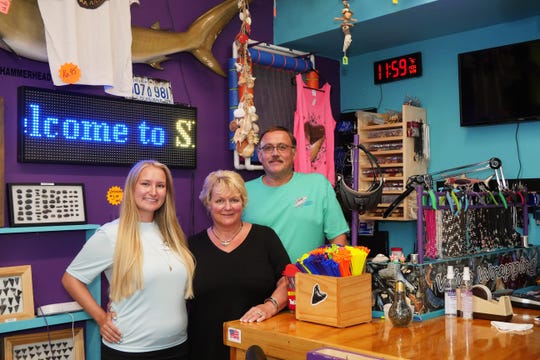 Brittanie Hervas poses with her parents Linda and Roy Hervas behind the counter at Shark Frenzy, the beachcombing store they opened up in December, 2019 on Tamiami Trail.