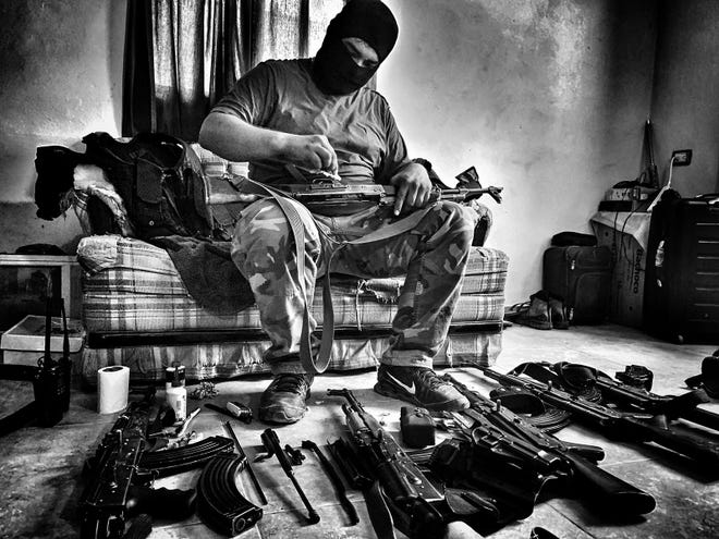 A soldier from the Sinaloa drug cartel cleans guns in the National Geographic documentary on migration "Blood on the Wall." Guest columnist Bernie Moreno is in favor of having Mexican cartels designated as foreign terrorist organizations (FTOs).