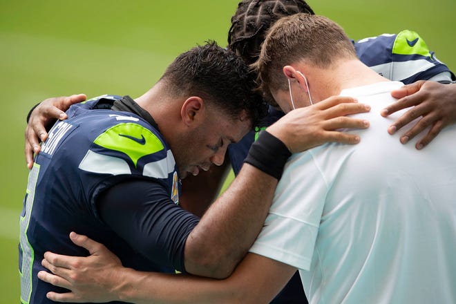 Seattle Seahawks quarterback Russell Wilson (3) prays with Seattle Seahawks quarterback Geno Smith (7) and a coach during the National Anthem at Hard Rock Stadium in Miami Gardens, October 4, 2020.
