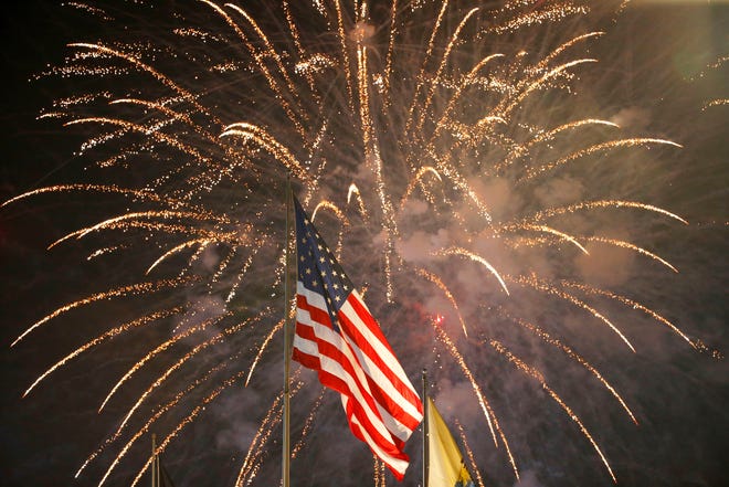 Fireworks behind a United States flag on July 4, 2015, in  East Rutherford, New Jersey.