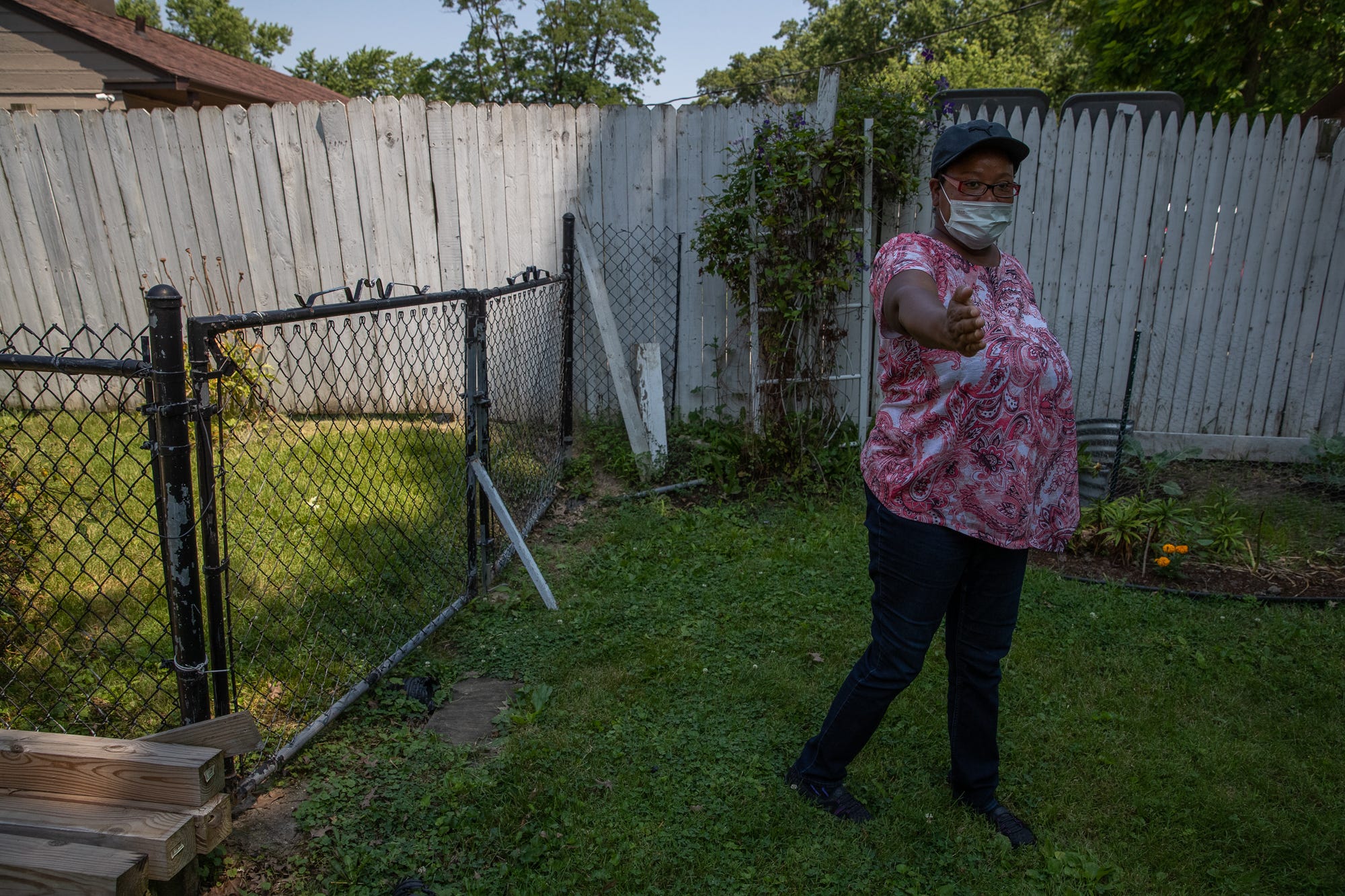 Ella White, daughter of Gordon Mitchum, points out the path an IMPD K-9 officer walked outside Mitchum's home when searching for a suspect in a carjacking that ended on Mitchum's street, on Monday, July 6, 2020. "This is the way he always keeps the fence, so they had to have jumped over the fence," she said. White then described using bleach and water to clean up the mass amount of blood left on her father's patio. 