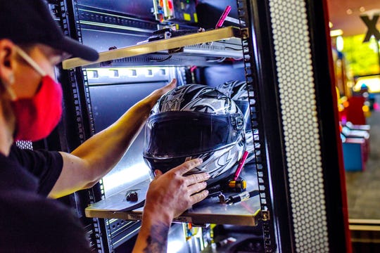 Casey Steele, operations manager, cleans a helmet in a new infrared cleaning station on Monday, Oct. 5, 2020, at High Caliber Karting and Entertainment in the Meridian Mall in Meridian Charter Township.