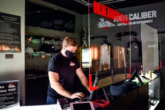 President Jordan Munsters works at a computer behind a partition recently installed to reduce the possible spread of infection on Monday, Oct. 5, 2020, at High Caliber Karting and Entertainment in the Meridian Mall in Meridian Township.