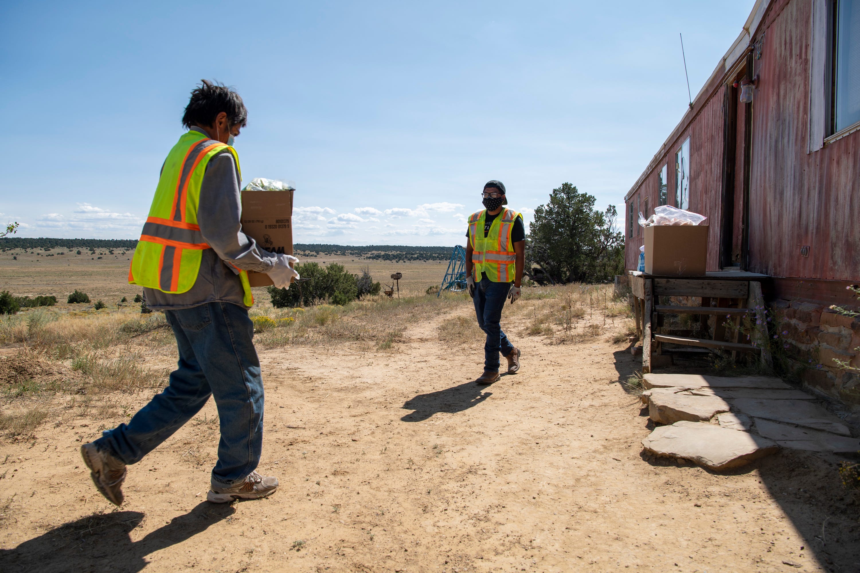 David Martine, left, and Vernard Martinez, right, deliver supplies to the home of Gilbert Martinez on the Ramah Navajo Indian Reservation.