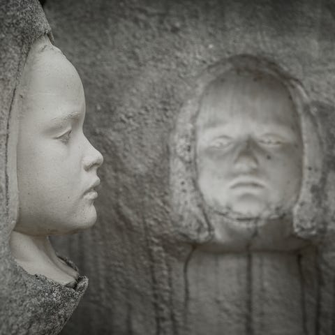 Statues of children encased in concrete blocks wel