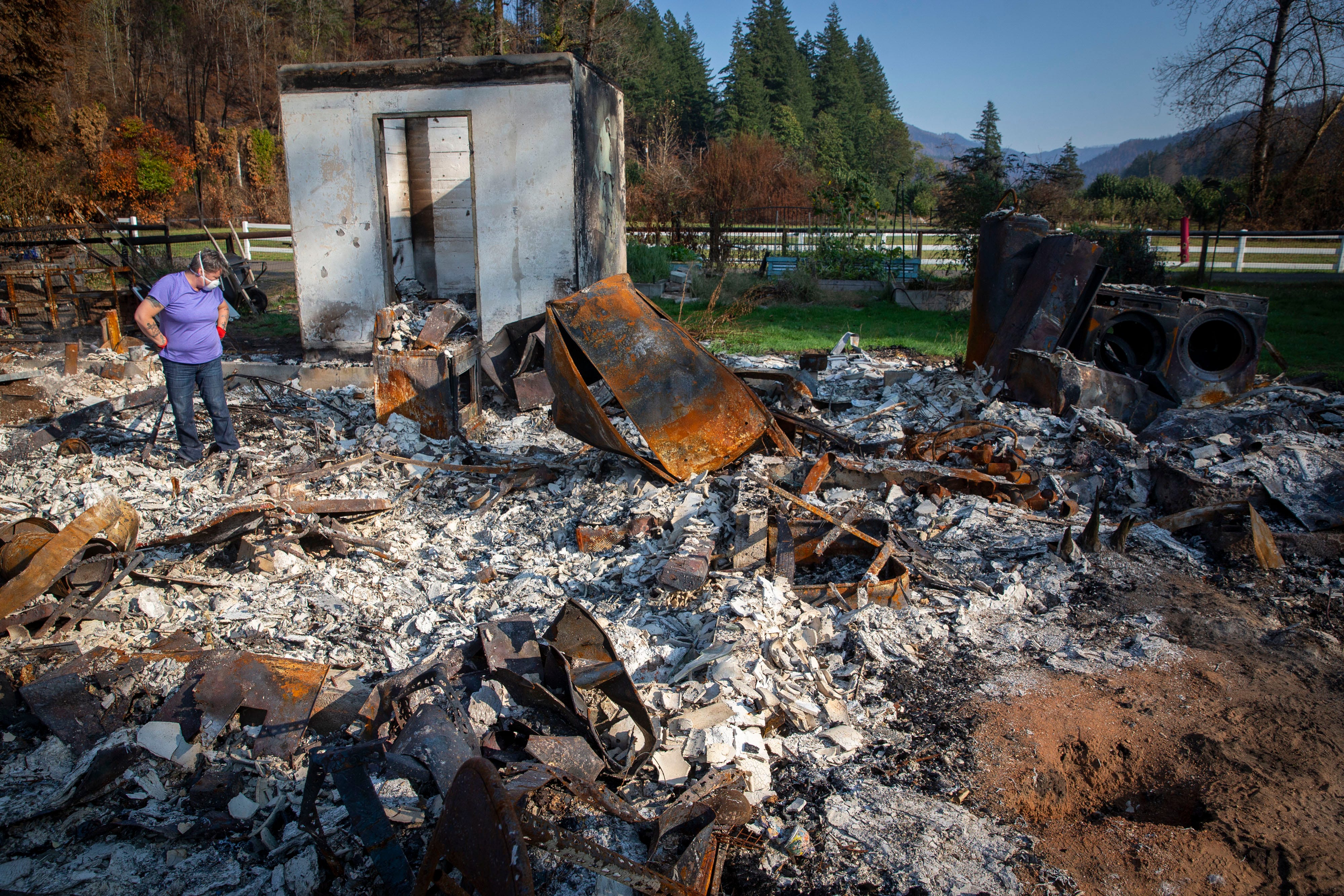 Upper McKenzie Fire Chief Christiana Rainbow Plews searches through the burned remains of her Vida home. FEMA and Oregon are encouraging residents with burned property to first try to get assistance from the government before cleaning up.