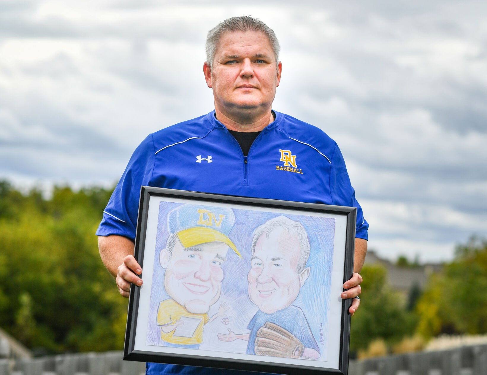 Cory Wachal holds a caricature drawing of himself and his father, Don, who died earlier this year of complications related to COVID-19.