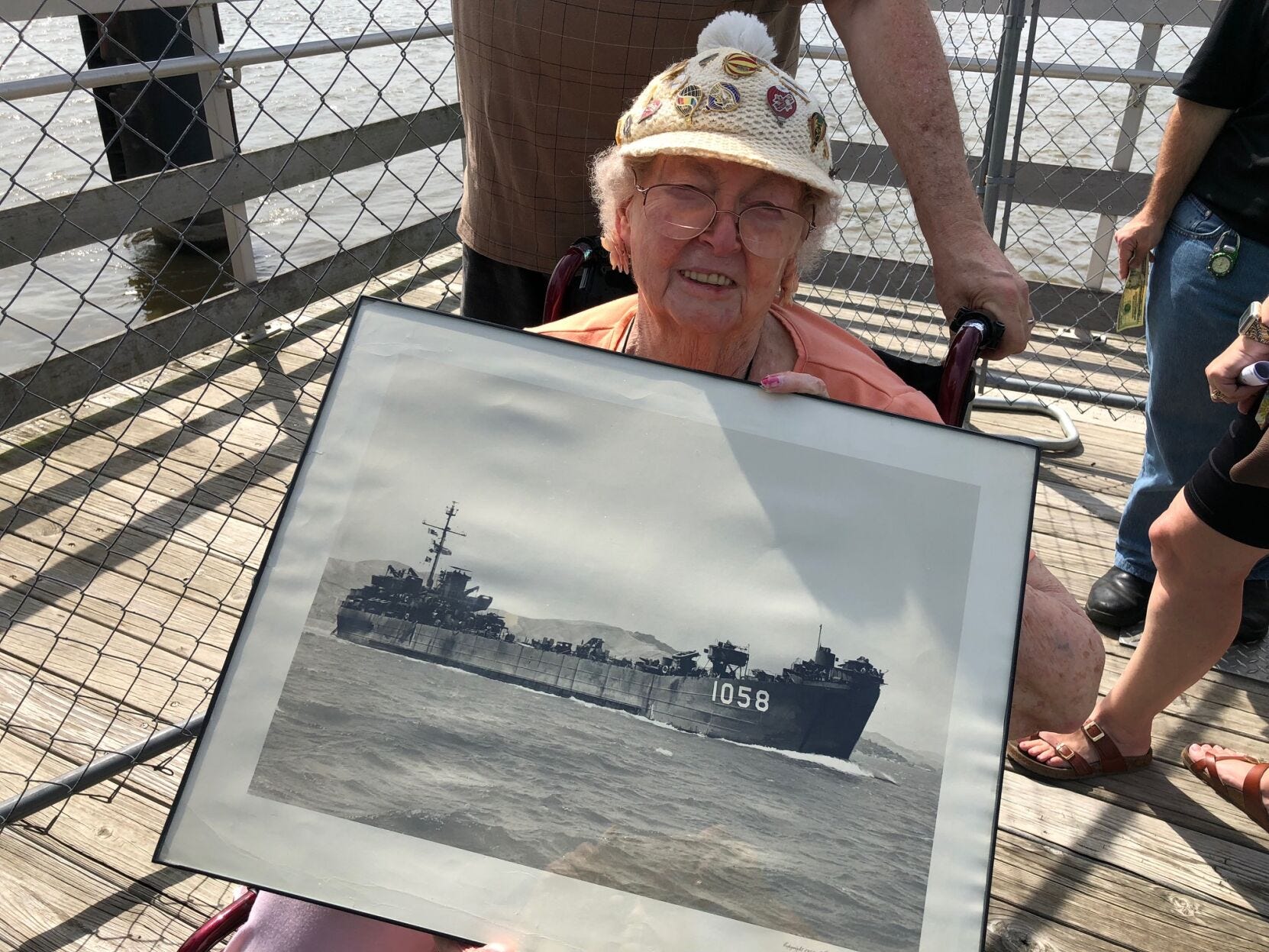 Phyllis Morrison poses with a large picture of the landing ship tank that her husband, Donald, served on. This picture was taken when the family visited the last working LST on the Mississippi River.