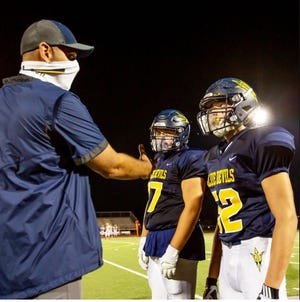Greencastle-Antrim assistant football coach Mike Hull, left, spoke with Jake Kumfert, center, and John Redos during the Oct. 2 game against Waynesboro. The coach wore a gaiter, while the players had protective shields in their helmets.