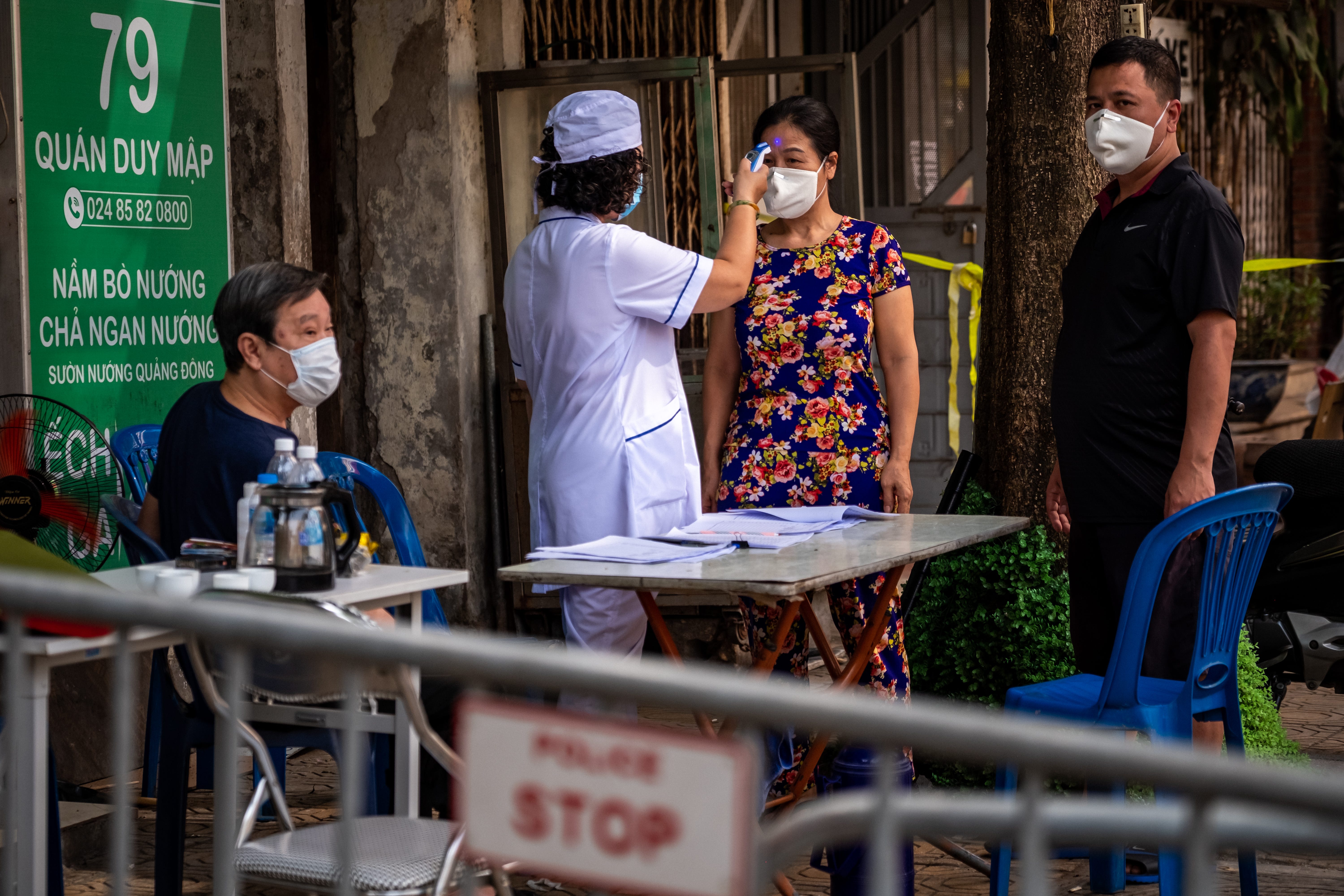 A health worker checks the temperatures of residents in the quarantined area of Truc Bach Street on March 9 in Hanoi. Authorities had blocked Truc Bach Street beginning March 6 to prevent the spread of COVID-19 after one resident, a 26-year-old Vietnamese woman recently back from Europe, contracted the virus.