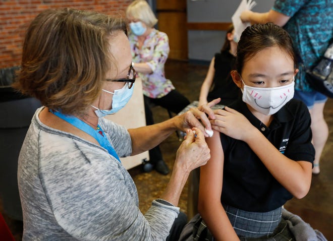 Lee Ann Neill, the coordinator of health services for Springfield Public Schools, gives fifth-grader Phoebe Lin a flu shot at the Discovery Center on Thursday, Oct. 8, 2020.
