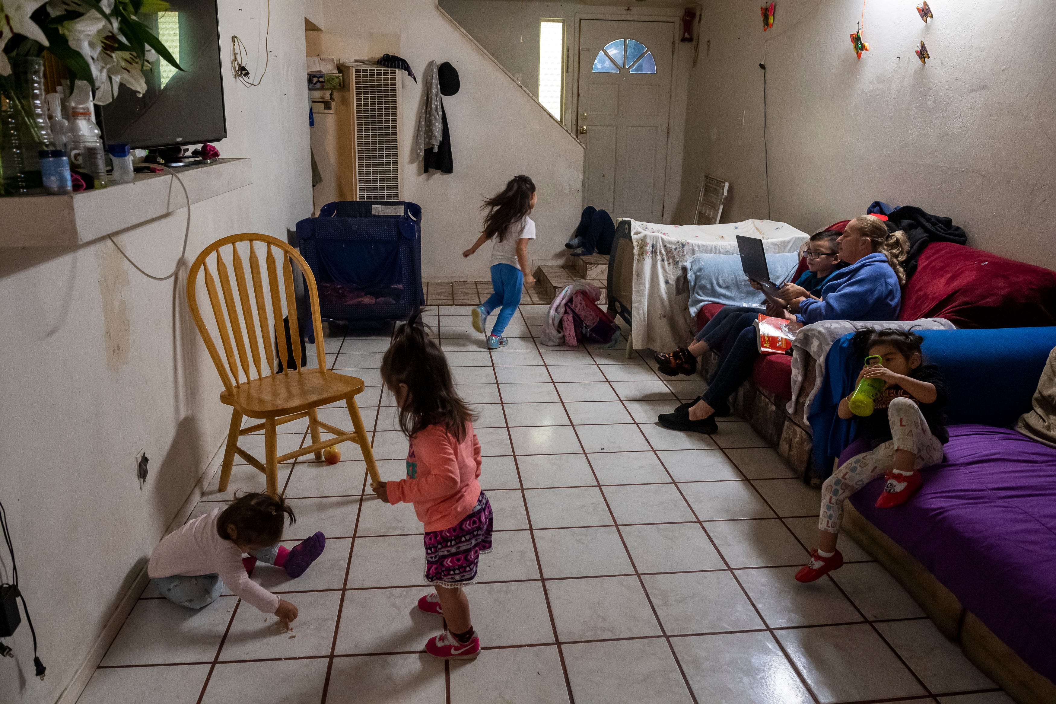 Four children surround Kender Ricardez Tobon, and  Eufemia "Jenni" Aguilar, as they both sit on the couch and work on Tobon's Chromebook in Salinas, Calif., on Thursday, Sept. 17, 2020. 