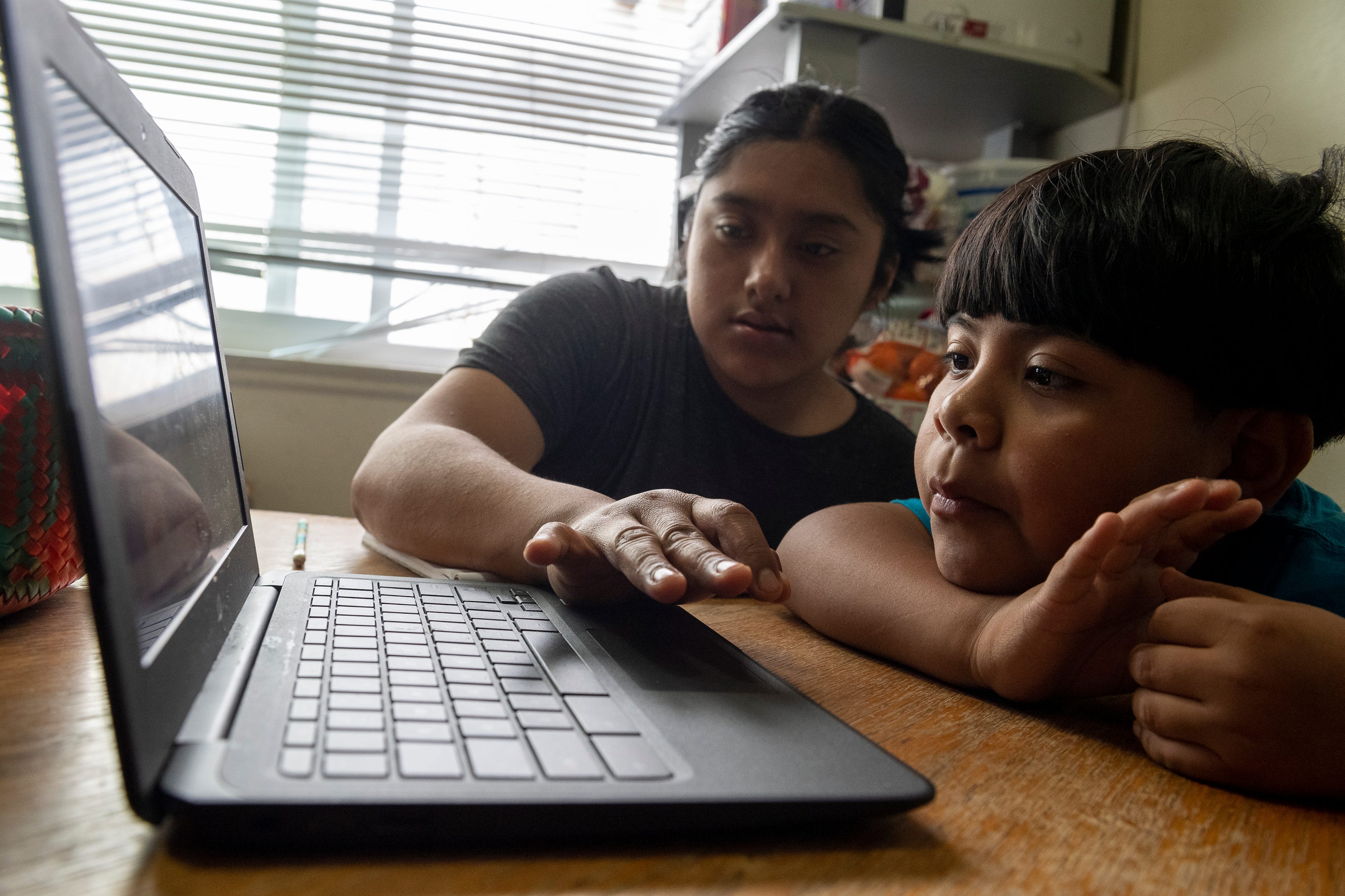 Resi Salvador, left, helps her brother Hugo Salvador, navigate his virtual class in Salinas, Calif., on Thursday, Aug. 13, 2020.