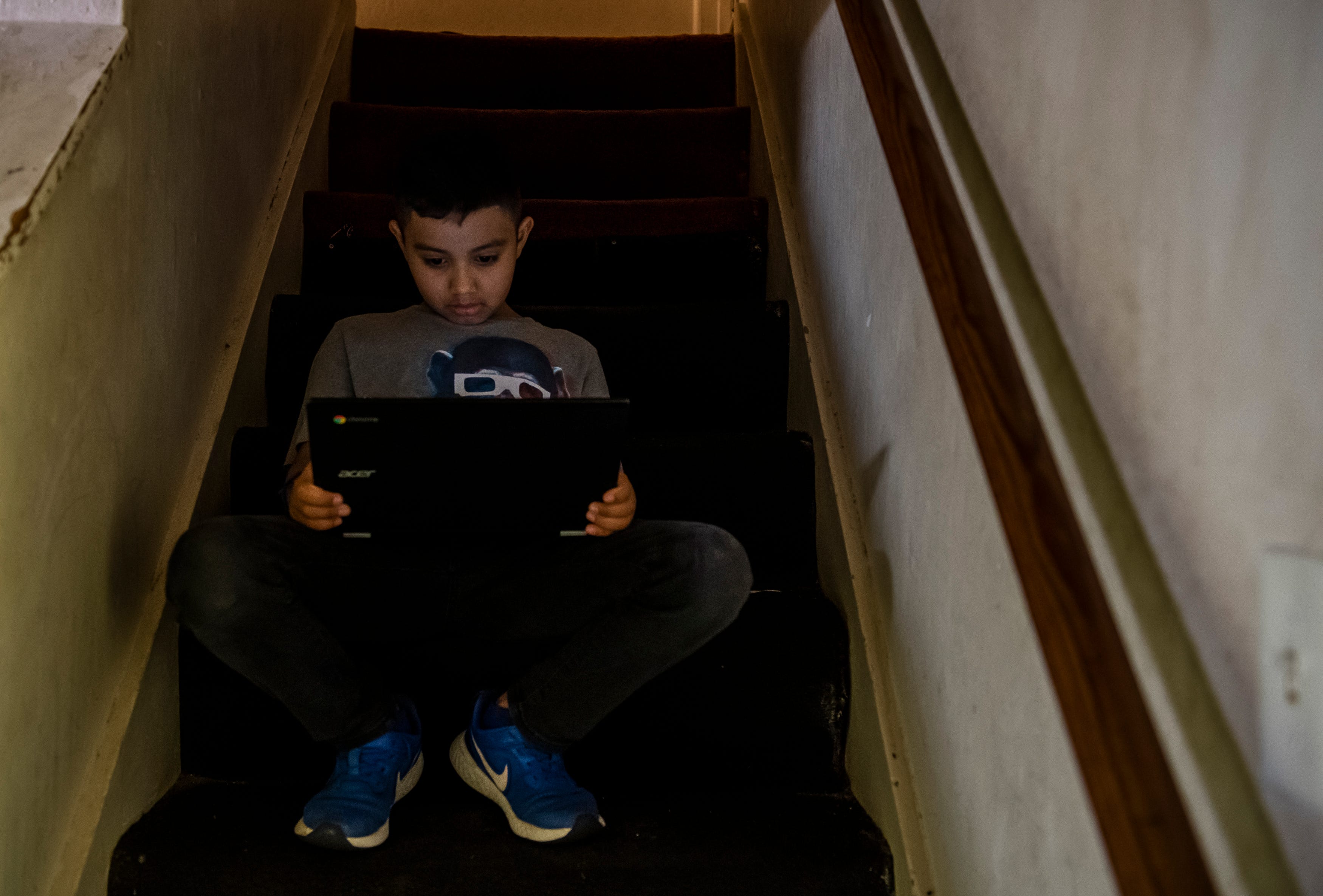 A young boy sits on the stairs and attend his virtual class inside his baby sitter's home in Salinas, Calif., on Thursday, Sept. 17, 2020.