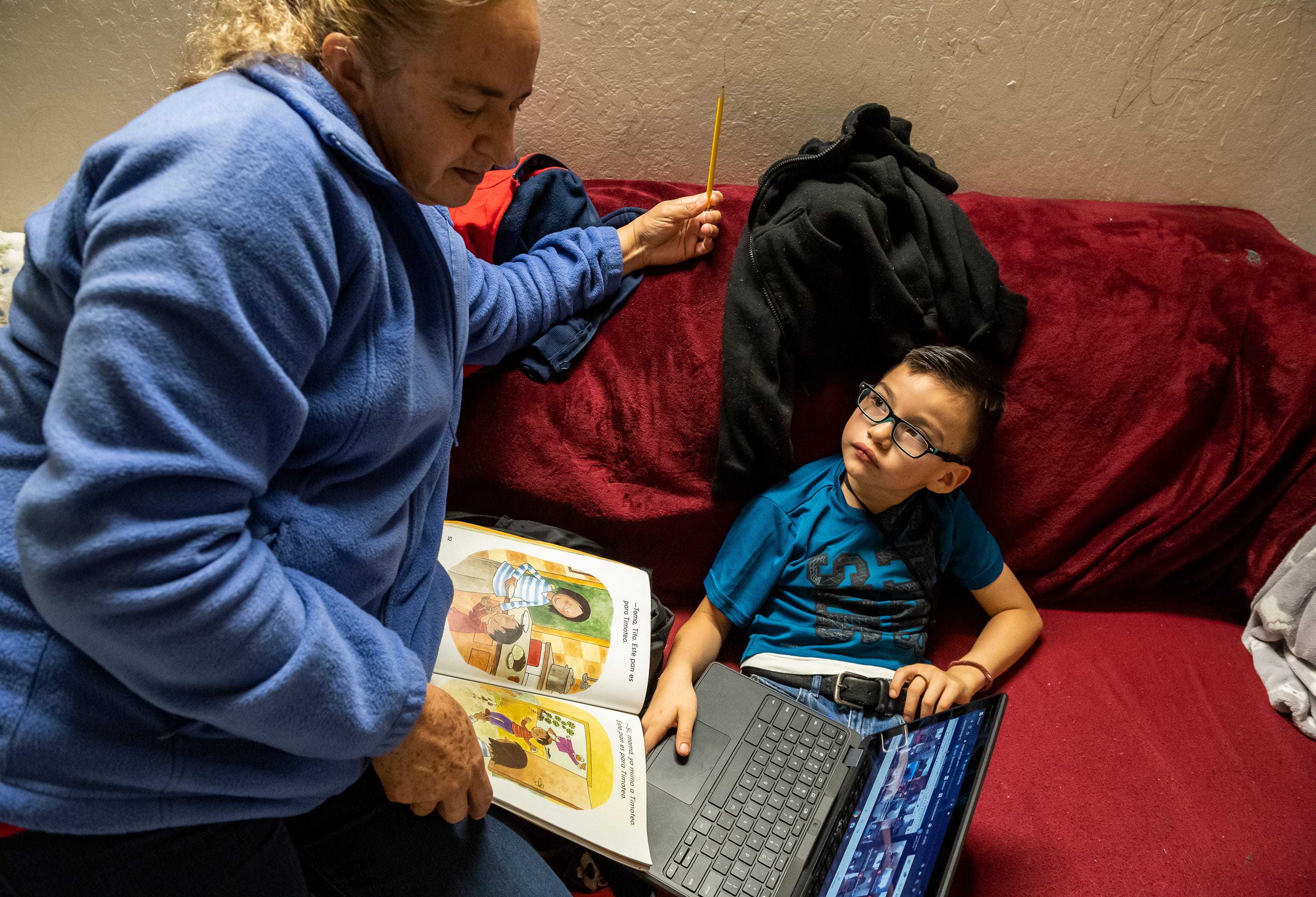 Eufemia "Jenni" Aguilar, helps her grandson Kender Ricardez Tobon read a book during Tobon's virtual class, as they both sit on a sofa at Tobon's babysitter's home in Salinas, Calif., on Thursday, Sept. 17, 2020.