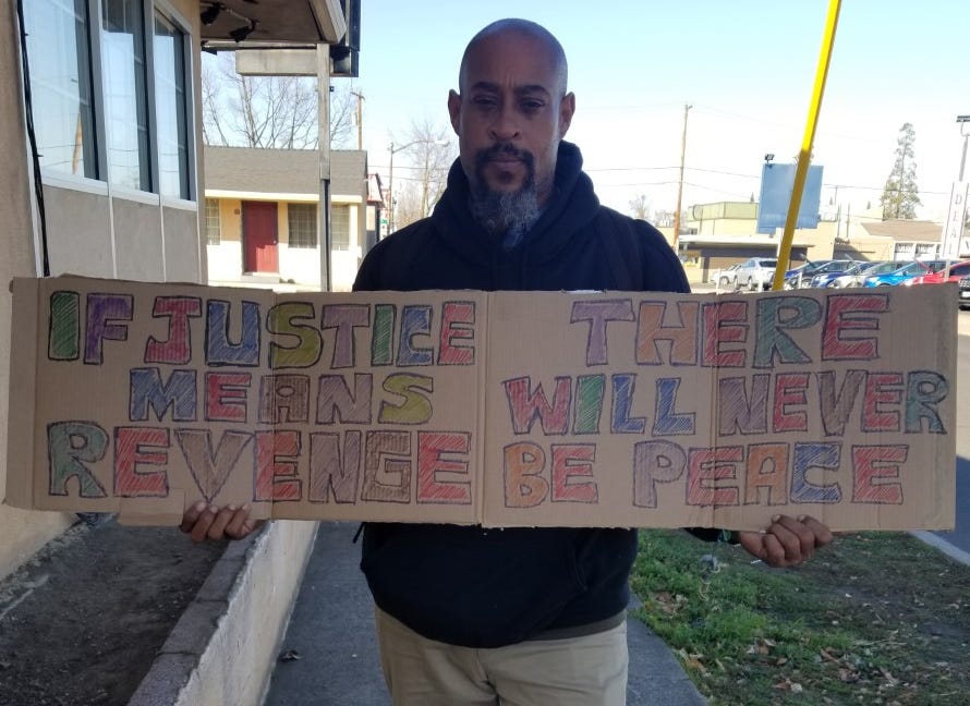 Kokayi Nosakhere holds a sign he made for the birthday of Martin Luther King Jr. He said he hoped his message would resonate with people no matter their skin color.