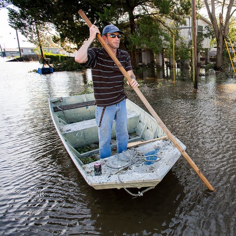 Len Moneaux poles his boat along a flooded street 
