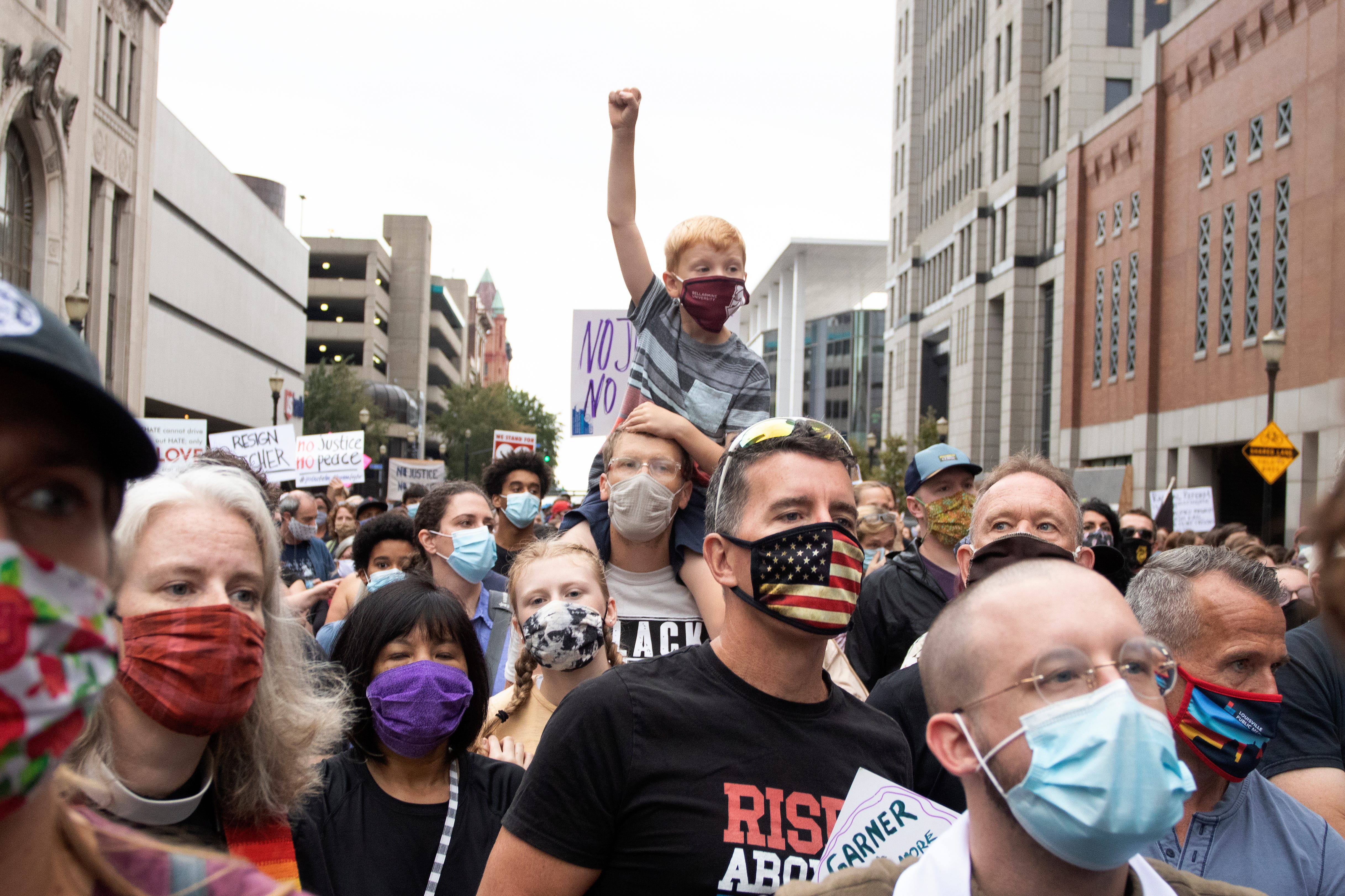 Justin Klassen carries his son on his shoulders during a march for racial justice through downtown Louisville. Oct. 10, 2020