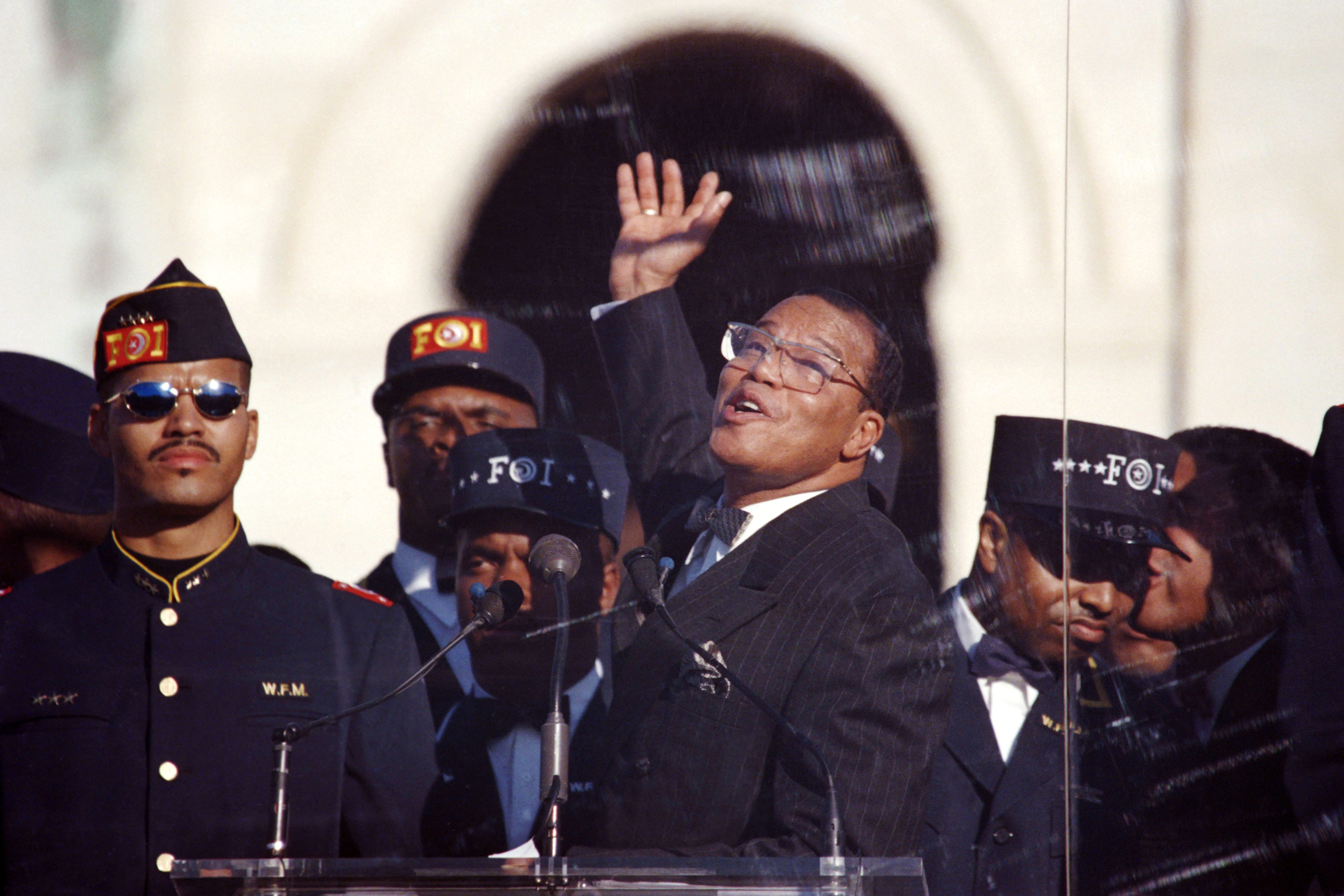 Nation of Islam leader Louis Farrakhan raises his hand behind bulletproof glass as he speaks in front of the Capitol Building at the Million Man March on Oct. 16, 1995.