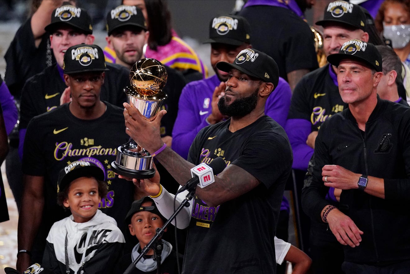 Los Angeles Lakers' LeBron James (23) holds the MVP trophy as he celebrates with his teammates after the Lakers defeated the Miami Heat 106-93 in Game 6 of the NBA Finals Sunday in Lake Buena Vista, Fla.